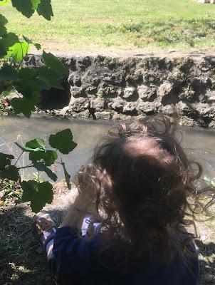 enfant assis devant une rivière et au milieu coule l'orge paisible