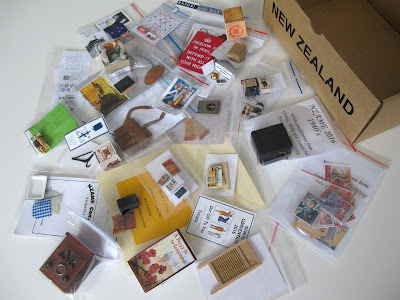 Empty cardboard box in the style of a Red Cross box, with a selection of 1940s-themed miniatures spread out in front of it.