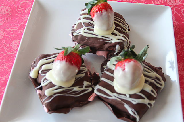 Three chocolate covered strawberry klondike bars sitting on a square, white plate.