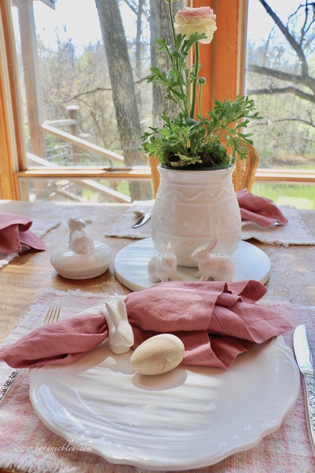 Easter tablesetting pink ranunculus centerpiece, rose linen napkins, wood egg, white ceramic egg vase, white ceramic salt and pepper shakers