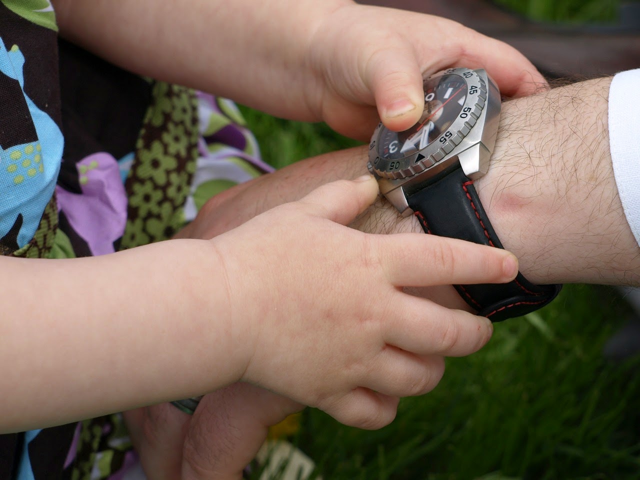 Kind spielt mit Uhr am väterlichen Handgelenk