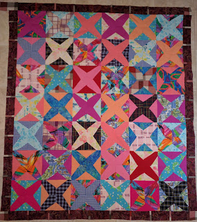 Pink, purple and blue shirts from a sister make strong Xs across this quilt.