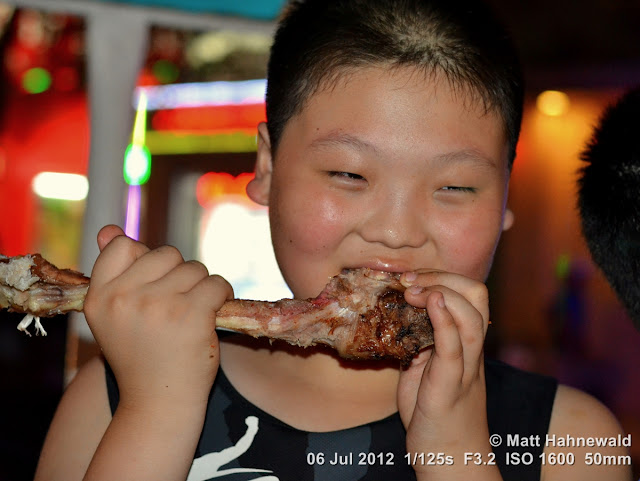 China, Beijing, Donghuamen night market, Chinese food delicacies, portrait, Chinese boy eating leg of lamb