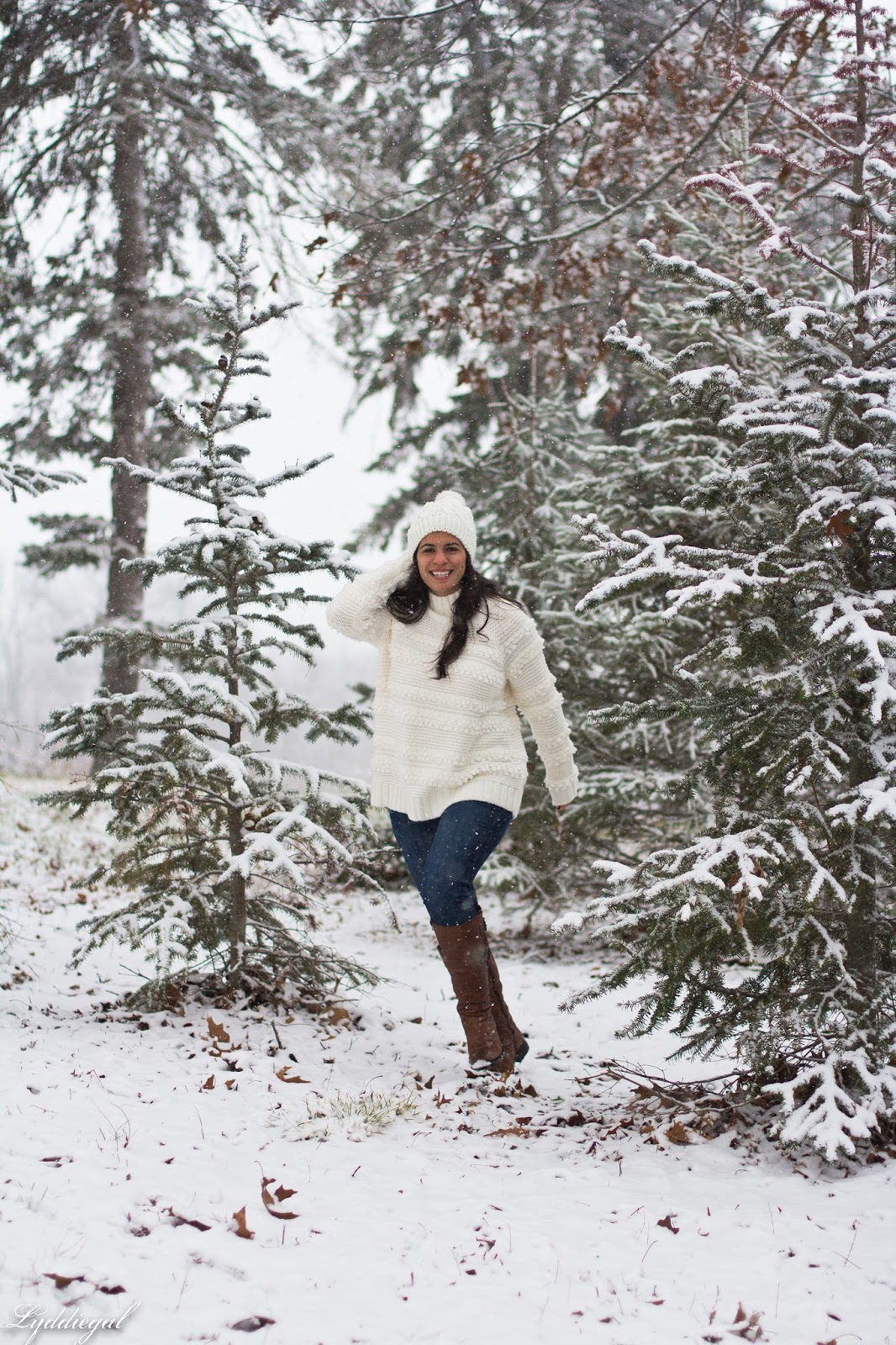CT Fashion blogger wearing a white sweater, pom pom hat and brown boots in the snow