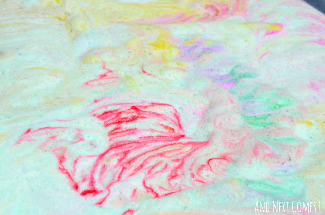 Close up of tie dye rainbow soap foam bubbles sensory play bin activity
