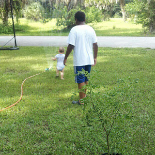 Big brother helping baby play in the water sprinkler and having fun with his brother.