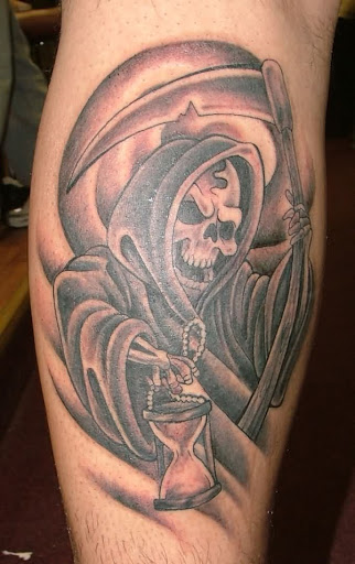 Uma sorridente Grim Reaper tatuagem. O reaper é visto estar segurando um copo de hora como se deliciosamente contar o tempo restante de uma alma, na terra dos vivos.
