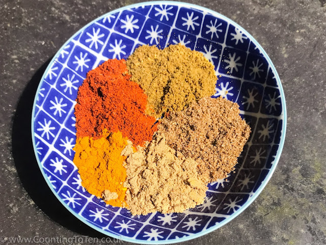 A dipping bowl with half teaspoons of 5 spices in it: paprika, tumeric, cumin, coriander and ginger