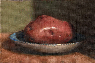 Oil painting of a Désirée potato on a blue and white saucer.