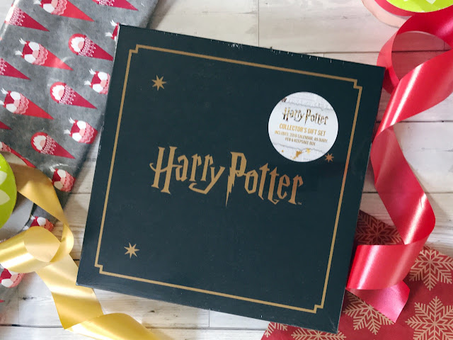Black box with gold writing and edging that reads Harry Potter, surrounded by wrapping paper and ribbon