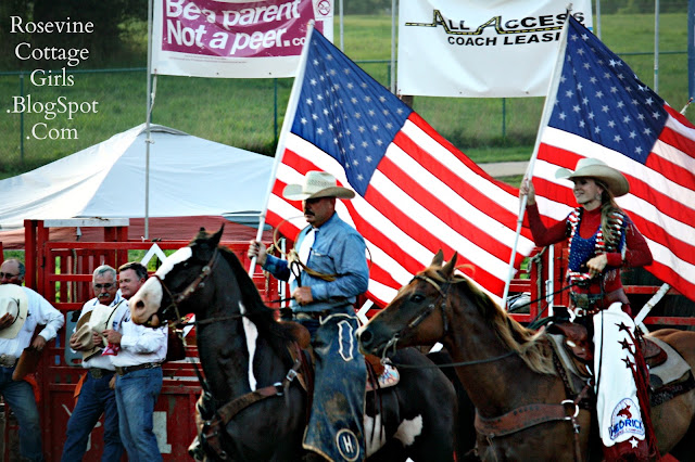 Cowboy and a cowgirl seated on their horses bearing old glory the flag of the United States of America at the Bold Enough Challenge Rodeo by Rosevine Cottage Girls.
