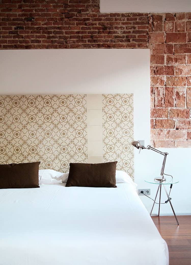 Dormitorio con azulejos hidraúlicos y pared de piedra