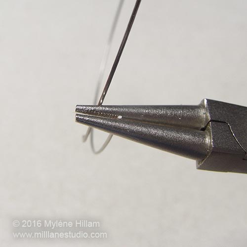 Holding the tip of the memory wire in the round nose pliers.