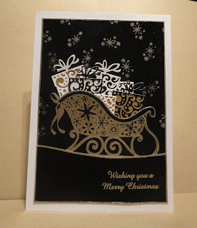 Black card with image of gold sleigh filled with presents, "wishing you a merry christmas" sentiment