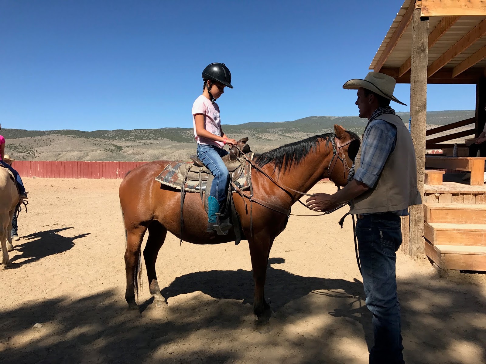 Female student sits on her horse listening to instruction from a dude ranch staff. 