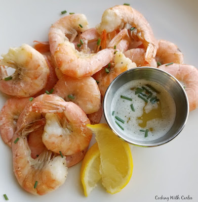 This roasted shrimp is kissed with the citrusy goodness of key lime juice. Dip them into lime butter for an extra special treat. They are like taking a bite of Florida. looking down on dinner plate of key lime roasted shrimp with dipping sauce and lemons