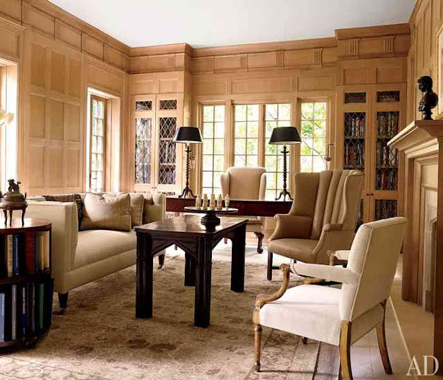 Home Office/Library with wood panelling, a fireplace, dark wood desk, accent table and coffee table, and a neutral sofa with matching armchairs
