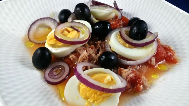 Una ensalada de tomate de bote, atún, cebolla y huevo