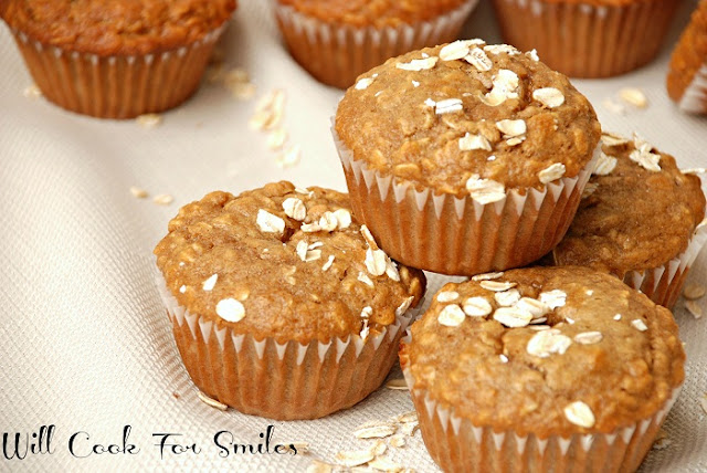 oat muffins stacked up on a cream colored table cloth with oats around it 