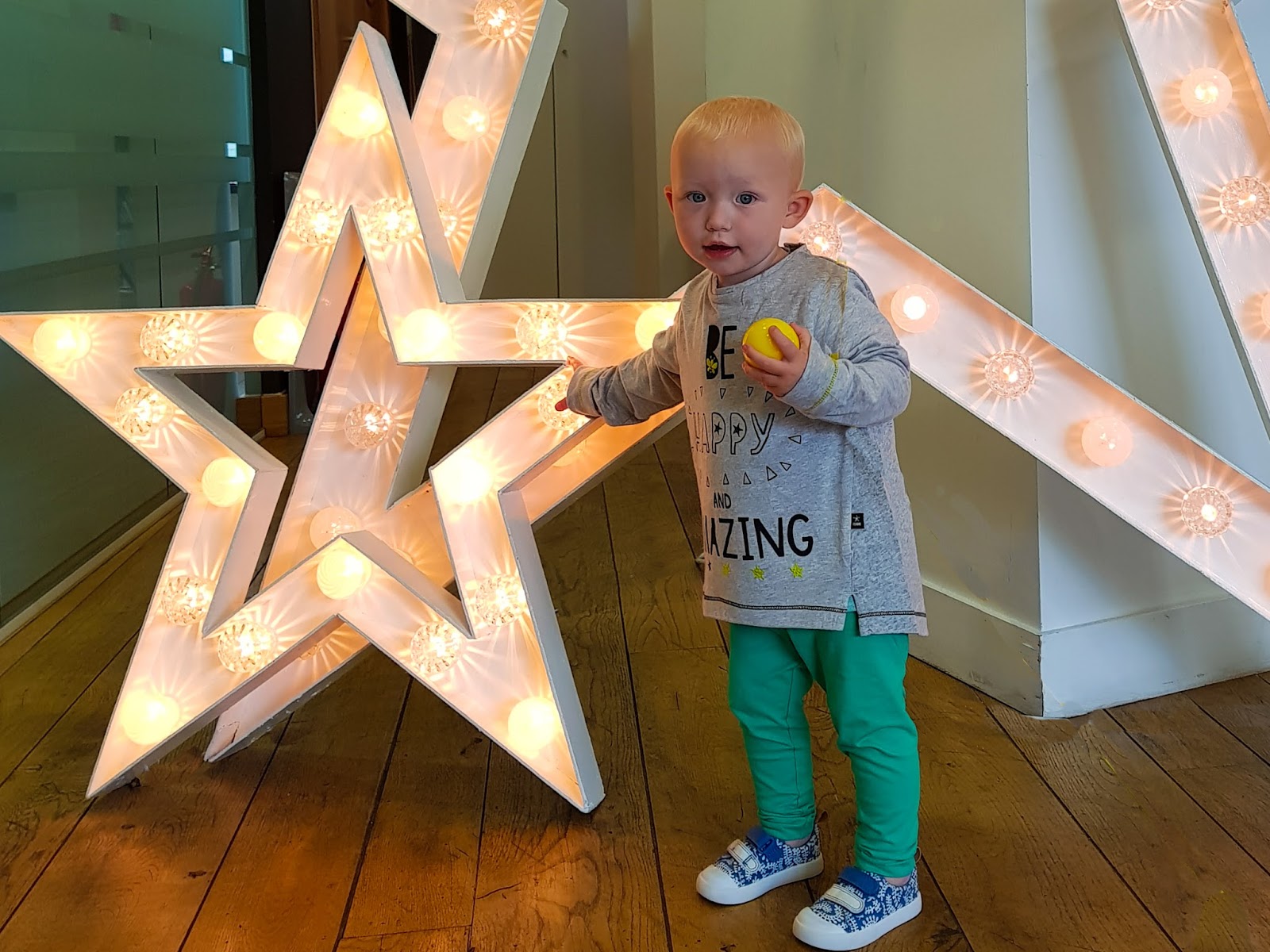 My toddler in a Boots Mini Club slogan tee in front of lit up stars