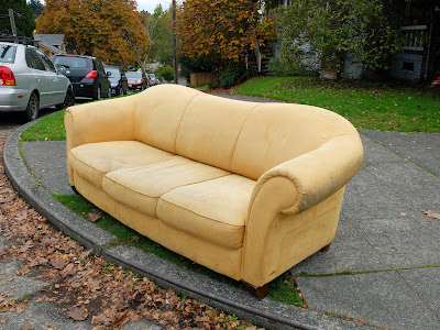 yellow couch sits curbside. 