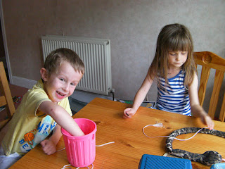 making necklaces out of beads and string on the dining table