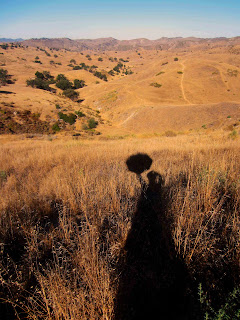 shadow_of_female_hiker_with_umbrella_against_brown_dry_hills_hiking_Mary_Poppins_shadow