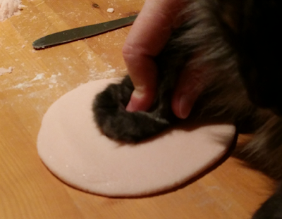Pushing cat paw into salt dough to make a keepsake