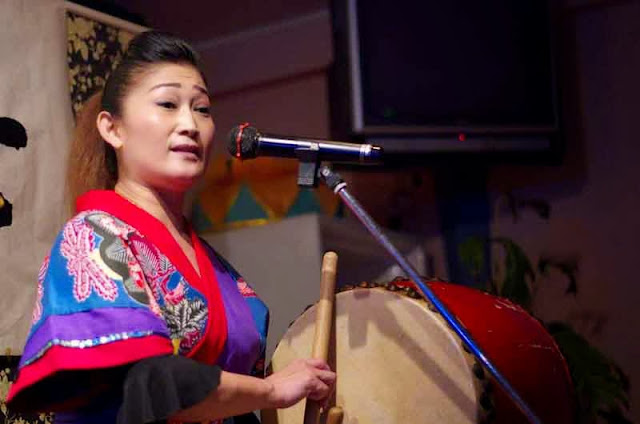 woman sings and plays drum in  okinawa