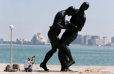 A photographer takes pictures of a bronze sculpture by French Algerian born artist Adel Abdessemed during its installation on October 4, 2013 on the Corniche in Doha after it was bought by the Qatar Museums Authority. The statue, titled Coup de Tete immortalizes the headbutt given by the French former football champion Zinedine Zidane to Italian player Marco Materazzi during the World Cup final in 2006.