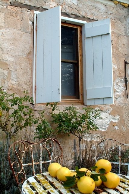 French chateau with blue shutters, iron furniture, and lemons found on Hello Lovely Studio