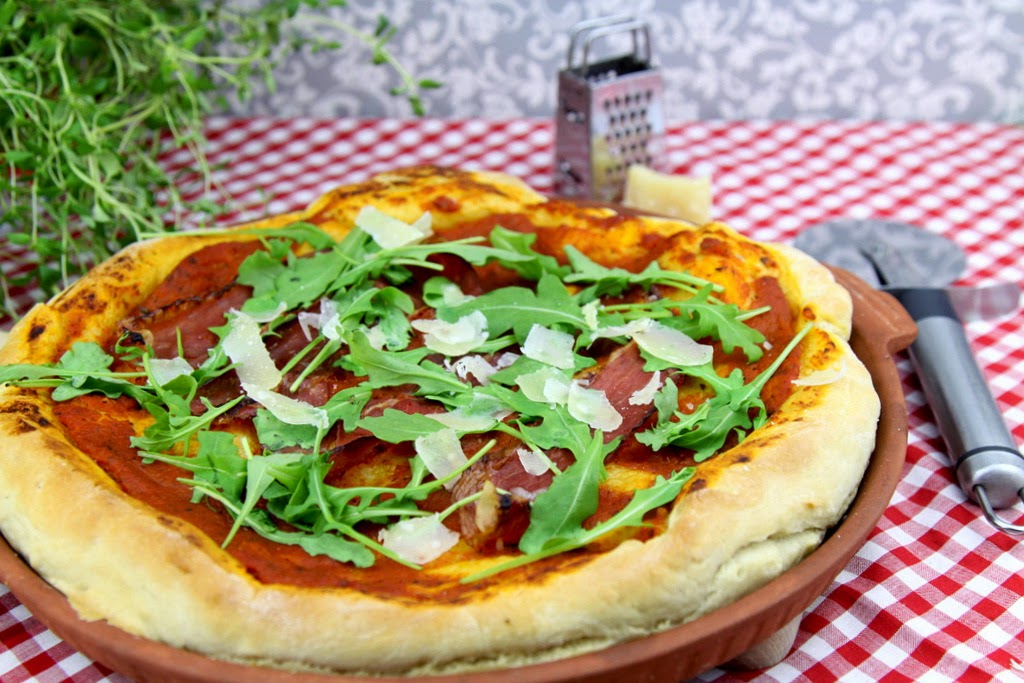 Włoska pizza z szynką, rukolą i parmezanem