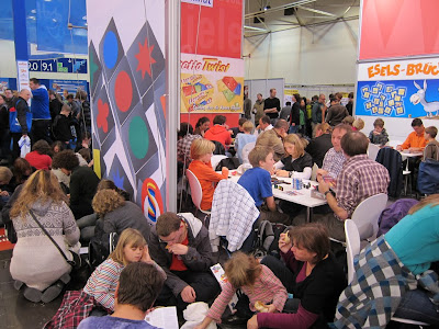 A photo at Spiel 2011 taken in Hall 11 showing the people sitting at tables and in the aisles playing games