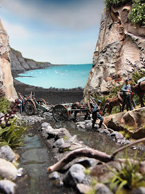 Diorama of 19th-century soldiers crossing a creek by the sea.