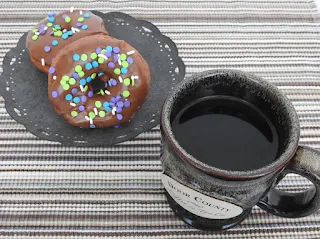 Chocolate frosted doughnuts with sprinkles and coffee