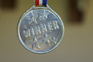 silver medal with embossed stars and the word winner