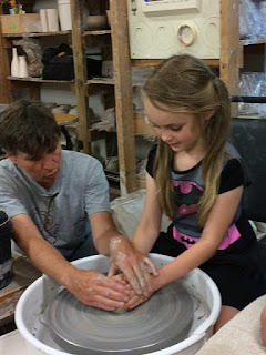 Teaching children centering clay on the potter’s wheel by Lori Buff