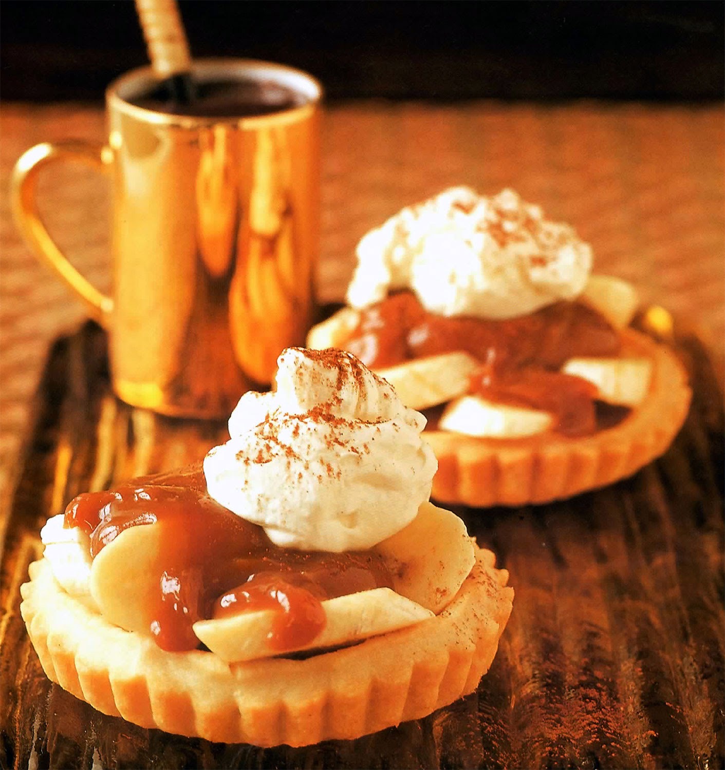 Banoffee Tarts Recipe: Miniature banoffee pies in a baked shortcrust shell, topped with whipped cream and fudge sauce