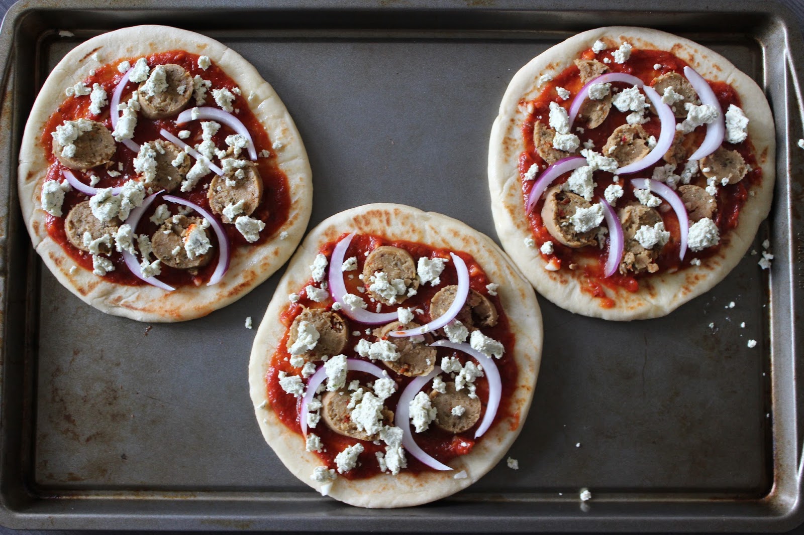 A Hoppy Medium Garlic Naan Pizzas with Goat Cheese, Sausage, and Onion