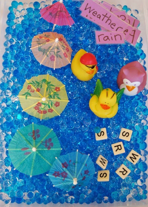 rainy day sensory bin with rubber ducks, paper umbrellas, water beads