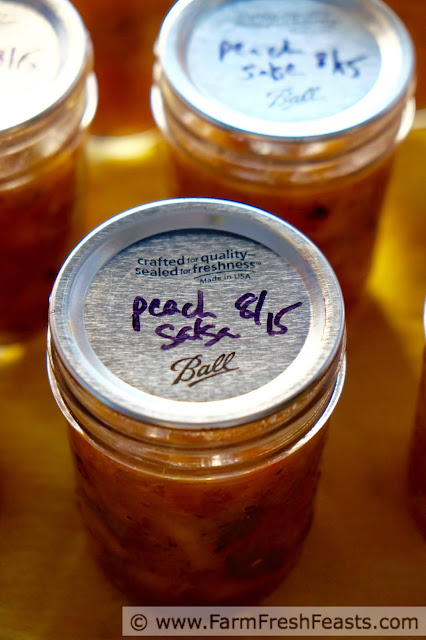 a close up of a jar of peach salsa with golden plums and roasted Hatch chiles