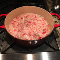 Cooking Dijon mustard ingredients. https://trimazing.com/ Photo of red stockpot with Dijon mustard ingredients, including: red onion, white wine, vinegar, salt, garlic, black peppercorns, rosemary. https://trimazing.com/
