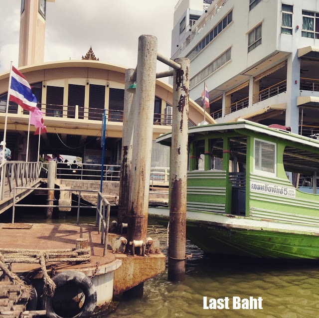 docks a green wooden ferry boat at a dock in Thailand