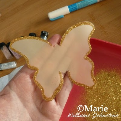 Adding extra fine gold glitter around the edges of a Vellum paper butterfly