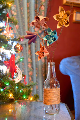 paper flowers in glass bottle wrapped in twine