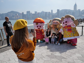 Family being photographed with a sculpture of the pig cartoon character McDull at the Avenue of the Stars