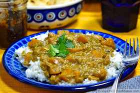 photo of a plate of green tomato curry with butternut squash and chicken, served over rice