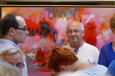 Profesor historii sztuki na tle czerwonego obrazu abstrakcyjnego, wernisaż malarstwa w galerii Wieża Sztuki