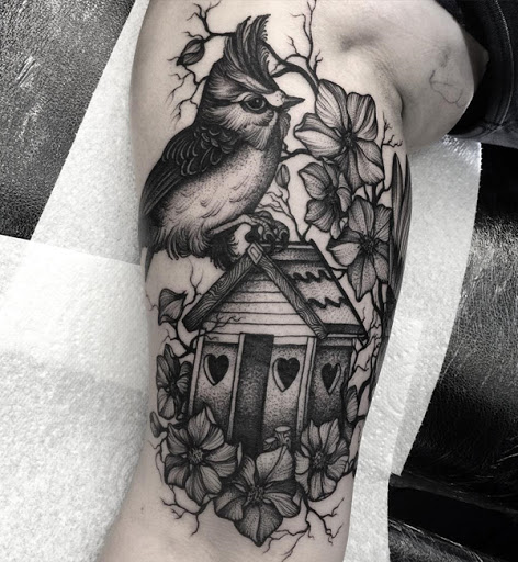 Um bonito e muito sleeve tatuagem. Os tons de cinza da tatuagem combina com o design perfeitamente. Você pode ver um pássaro empoleirado em uma casa de passarinho que parece estar-se em uma árvore repleta de flores. Tudo adorável combinados em apenas um projeto.