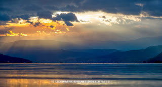 Scenic Crepuscular rays of light poke through the clouds on the Mountains of Okanagan Valley viewed from Kelowna by Chris Gardiner Photography www.cgardiner.ca